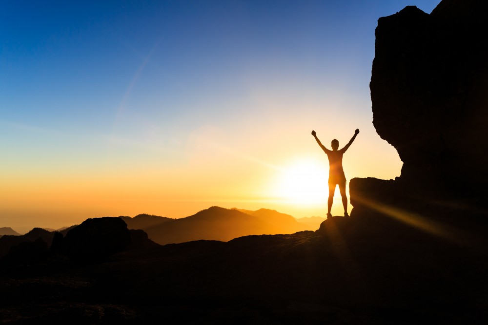 Woman climber success silhouette in mountains, ocean and sunset